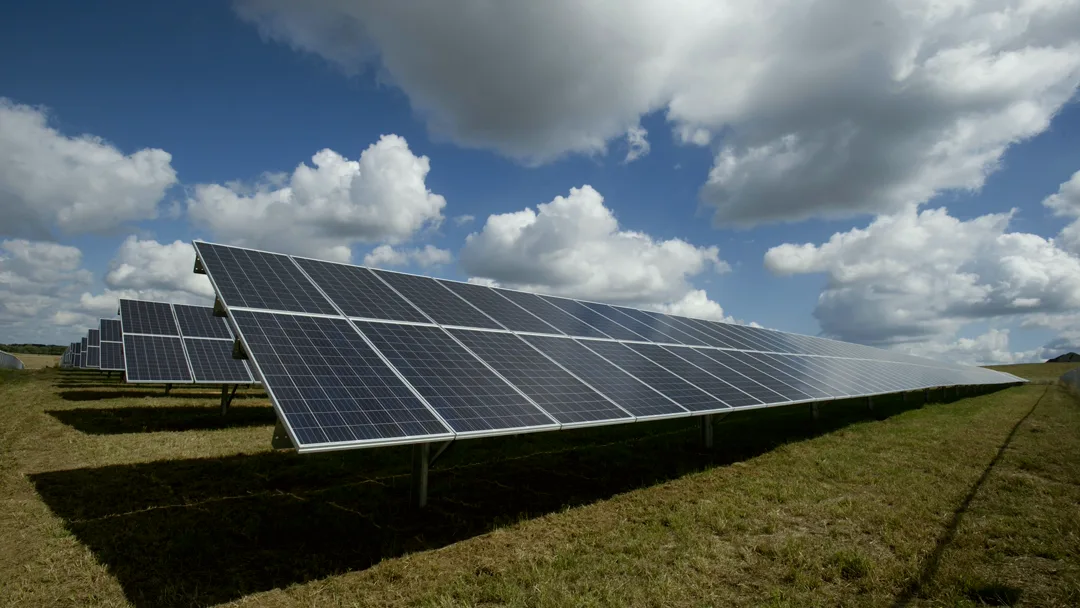 Paneles solares en un campo bajo un cielo con nubes, ejemplo de eficiencia energética