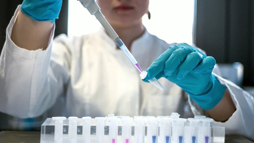 Científica utilizando una pipeta con tubos de ensayo en un laboratorio